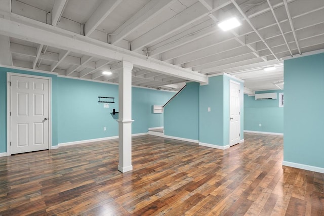 finished below grade area featuring hardwood / wood-style floors, baseboards, and an AC wall unit