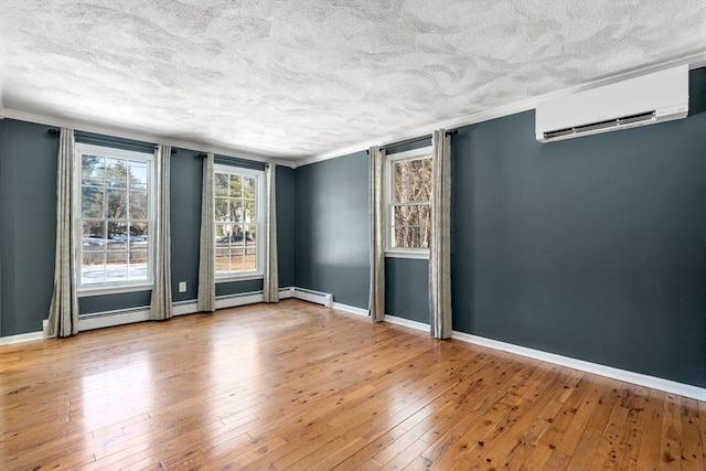 unfurnished room with baseboards, wood-type flooring, a wall mounted air conditioner, crown molding, and a textured ceiling