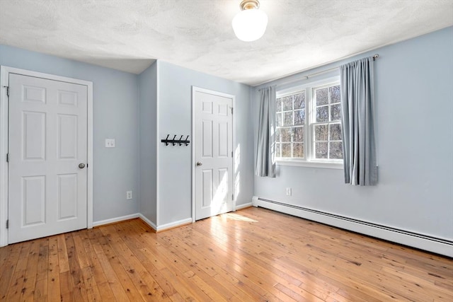 spare room with a baseboard radiator, light wood-style flooring, and baseboards