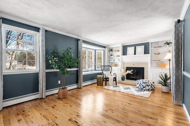 sitting room with built in features, a fireplace, wood-type flooring, ornamental molding, and a textured ceiling