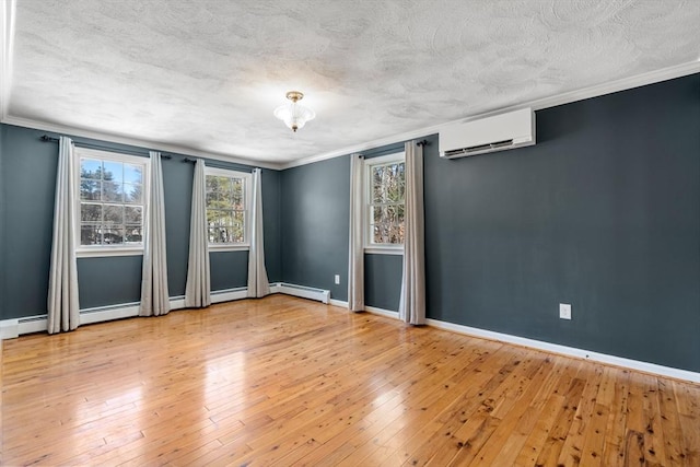 unfurnished room featuring a textured ceiling, a wall unit AC, wood-type flooring, and baseboards