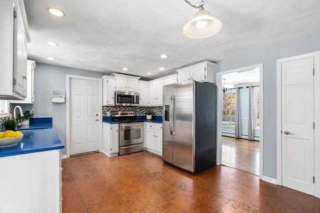 kitchen featuring stainless steel appliances, a sink, white cabinets, backsplash, and dark countertops