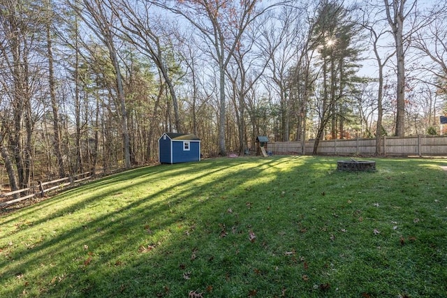 view of yard with a fire pit, a shed, an outdoor structure, and fence