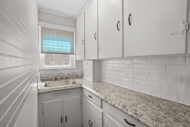 kitchen featuring white cabinets, light countertops, a sink, and backsplash