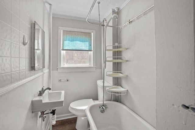 bathroom featuring toilet, a washtub, wood finished floors, and ornamental molding