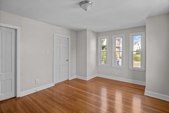 spare room with baseboards and wood finished floors