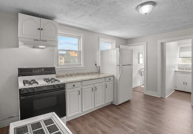 kitchen with white cabinetry, range with gas cooktop, freestanding refrigerator, and under cabinet range hood