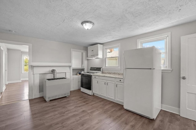 kitchen featuring range with gas stovetop, freestanding refrigerator, white cabinets, and wood finished floors