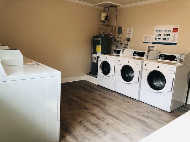 clothes washing area featuring washing machine and clothes dryer, crown molding, hardwood / wood-style flooring, and electric water heater