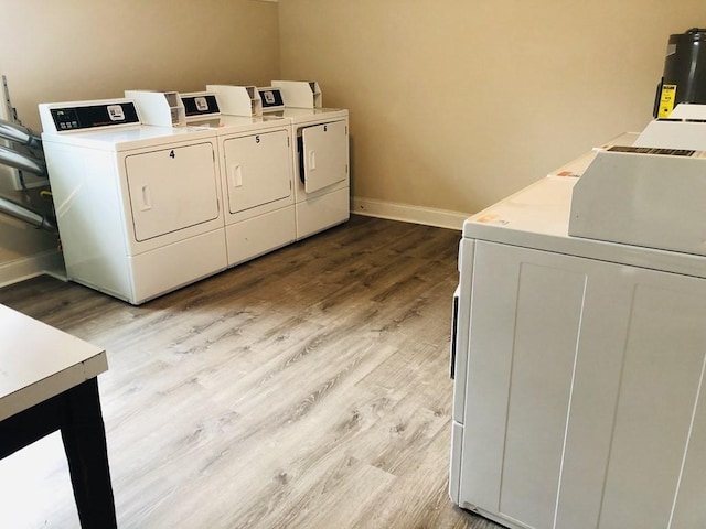 laundry room with water heater, light wood-type flooring, and washing machine and clothes dryer