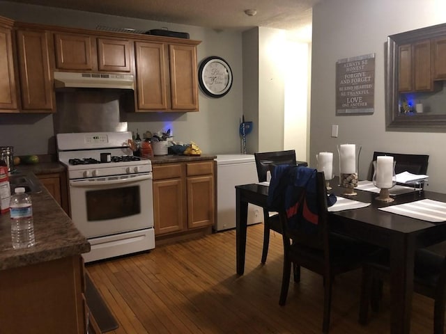 kitchen with white gas stove, refrigerator, and dark wood-type flooring