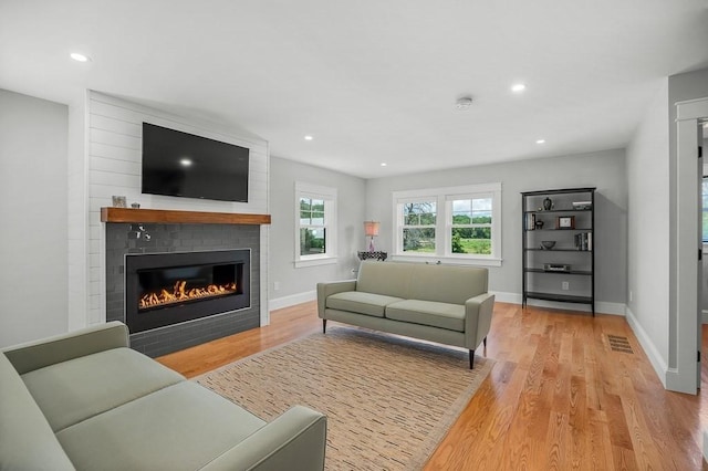 living room featuring light hardwood / wood-style flooring and a large fireplace