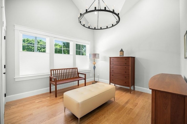 living area featuring high vaulted ceiling, light wood-type flooring, and an inviting chandelier