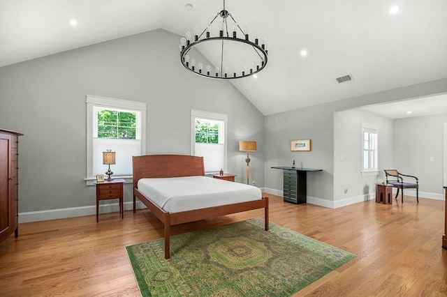 bedroom with high vaulted ceiling, an inviting chandelier, and light hardwood / wood-style flooring