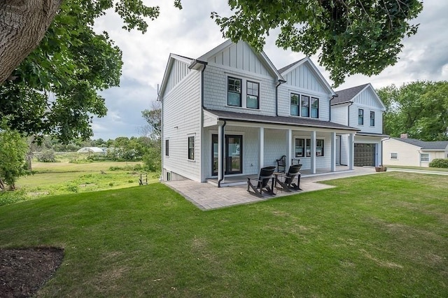 rear view of house with a garage, a lawn, a patio, and a porch