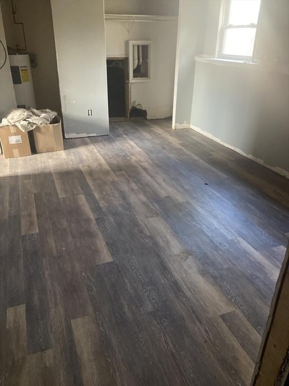 unfurnished living room with water heater, wood finished floors, and baseboards