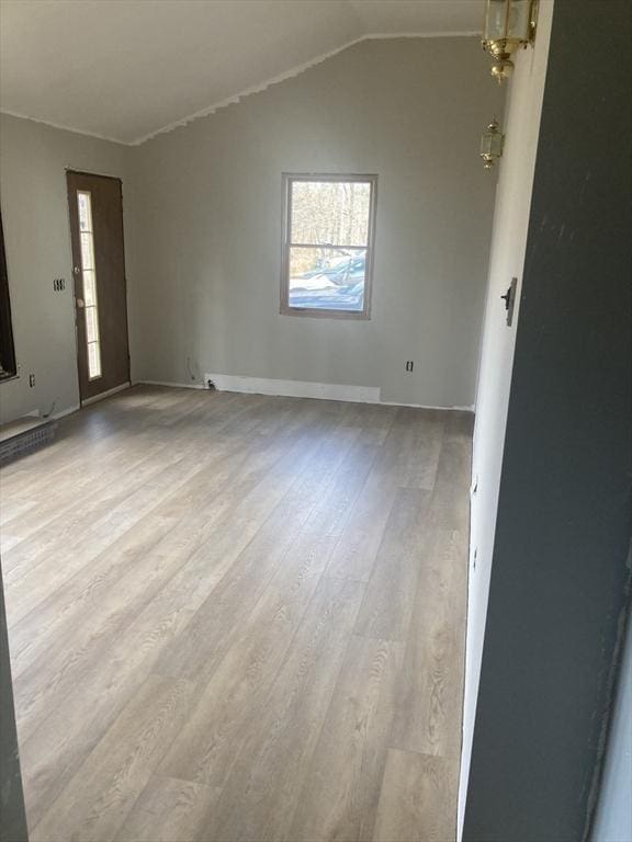 spare room featuring wood finished floors, lofted ceiling, and baseboards