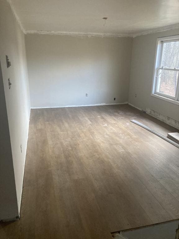 unfurnished room with wood finished floors, crown molding, and baseboards