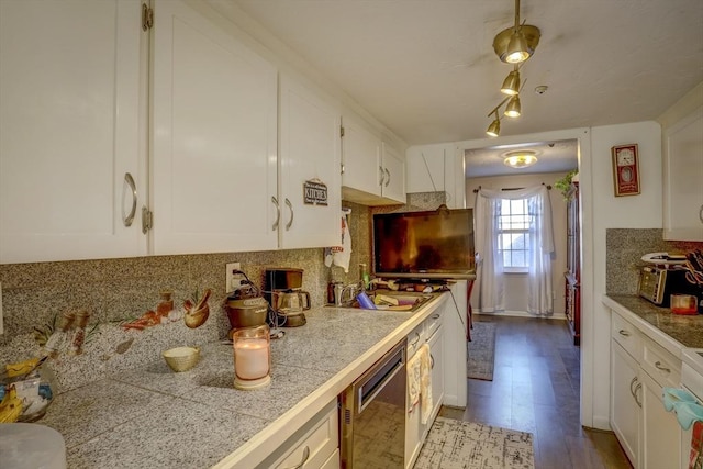 kitchen with light wood-type flooring, backsplash, stainless steel dishwasher, sink, and white cabinets