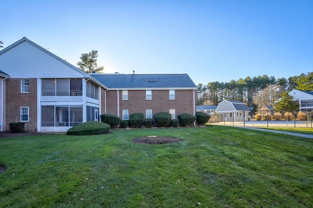 back of house featuring a yard, a shed, and a sunroom