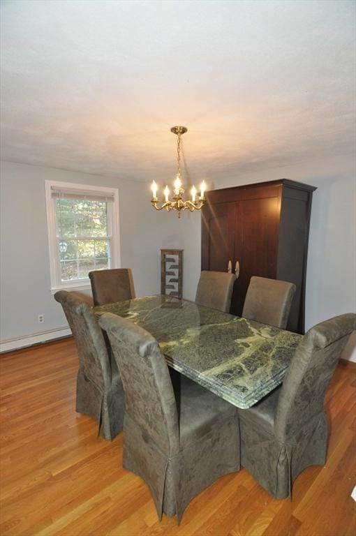 dining room with a notable chandelier, baseboards, and light wood-style floors