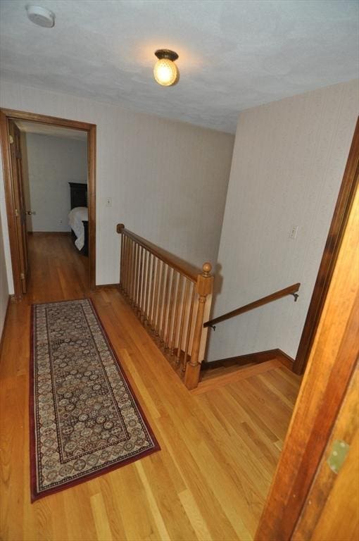 corridor with wood finished floors and an upstairs landing