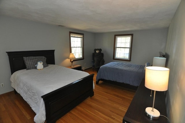 bedroom with baseboards, baseboard heating, and wood finished floors