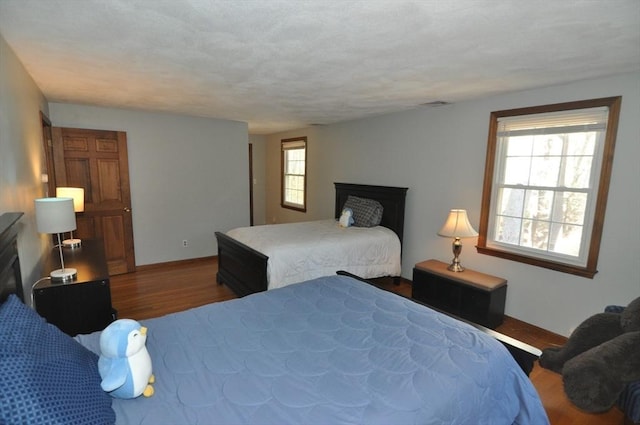 bedroom featuring a fireplace, baseboards, visible vents, and wood finished floors
