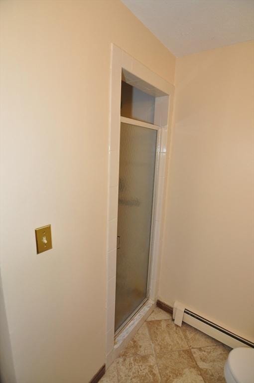 full bath featuring toilet, a stall shower, tile patterned floors, baseboards, and a baseboard radiator