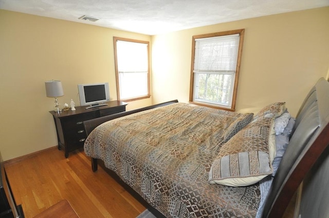 bedroom featuring visible vents, wood finished floors, and baseboards