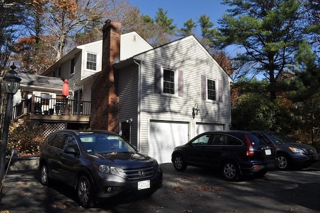 view of home's exterior with a chimney, driveway, and a garage