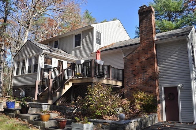 back of property featuring a chimney, a deck, and stairway