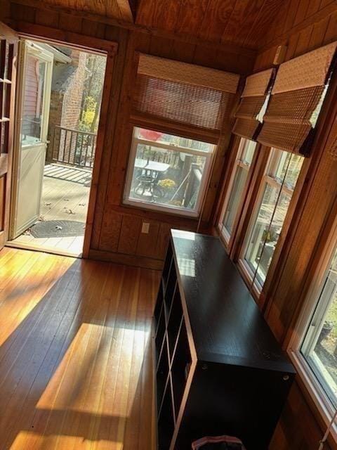 doorway to outside with wooden ceiling, wood walls, and wood-type flooring