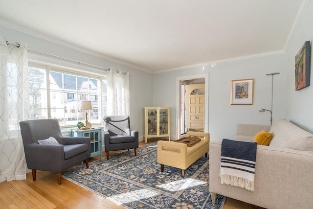 sitting room with ornamental molding and wood-type flooring