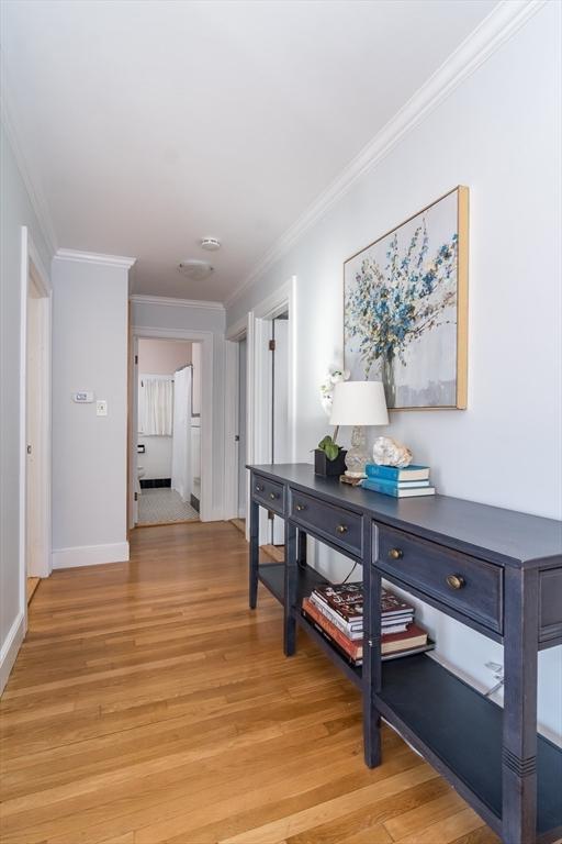 hall with crown molding and light hardwood / wood-style floors