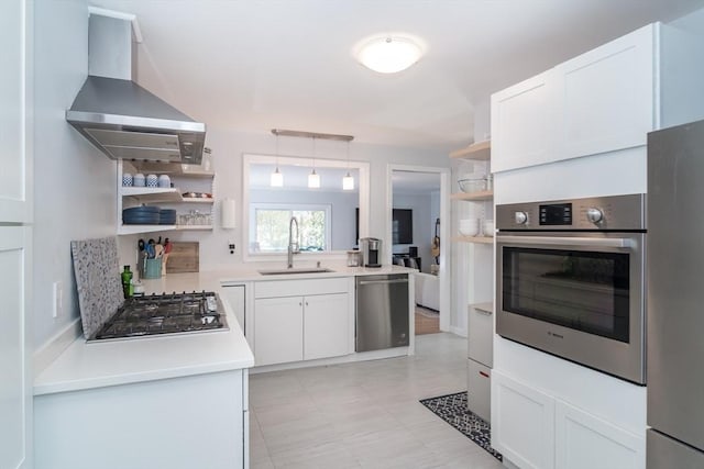 kitchen featuring pendant lighting, white cabinets, stainless steel appliances, and wall chimney range hood