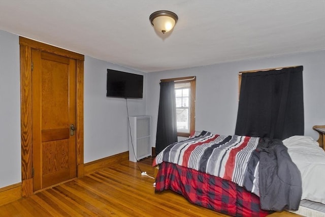 bedroom with radiator heating unit, baseboards, and wood finished floors