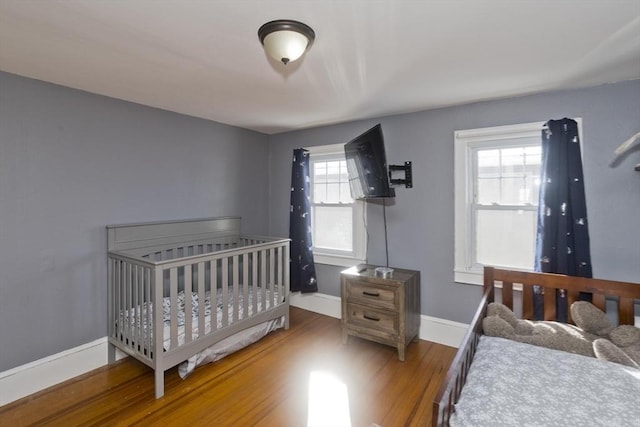 bedroom featuring multiple windows, baseboards, and wood finished floors