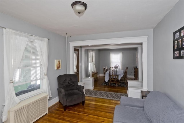 living area featuring dark wood-type flooring, radiator, and baseboards