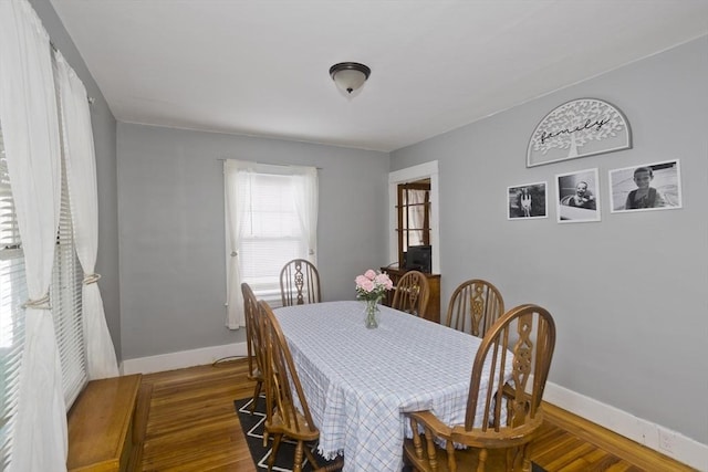 dining space with baseboards and wood finished floors