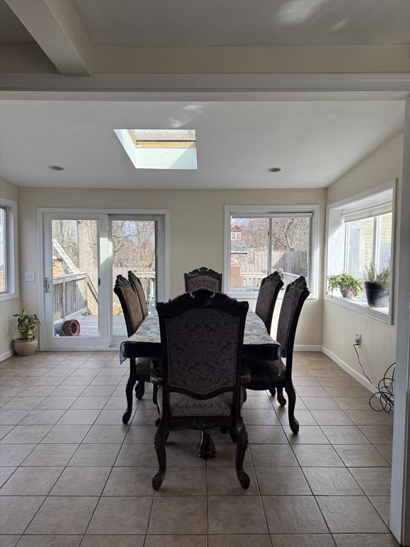 dining area with tile patterned flooring, a skylight, and baseboards