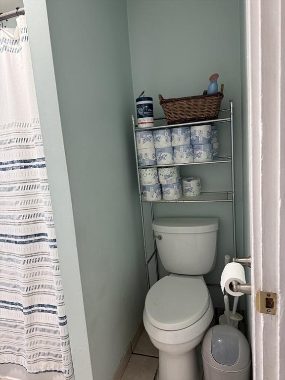 bathroom with curtained shower, baseboards, toilet, and tile patterned flooring