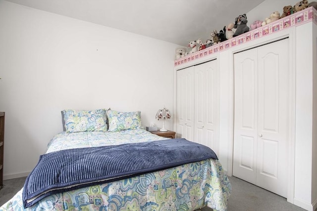 bedroom featuring light carpet, baseboards, and two closets