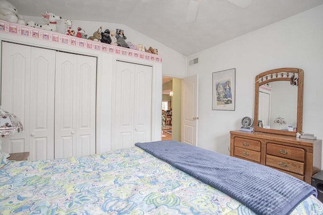 bedroom with lofted ceiling, a ceiling fan, visible vents, and multiple closets