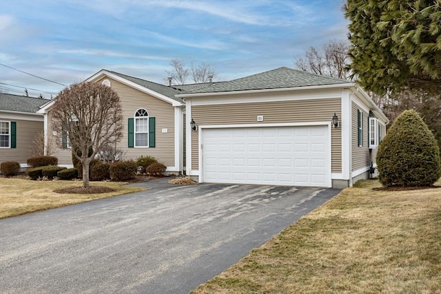 single story home with an attached garage, a front lawn, aphalt driveway, and roof with shingles