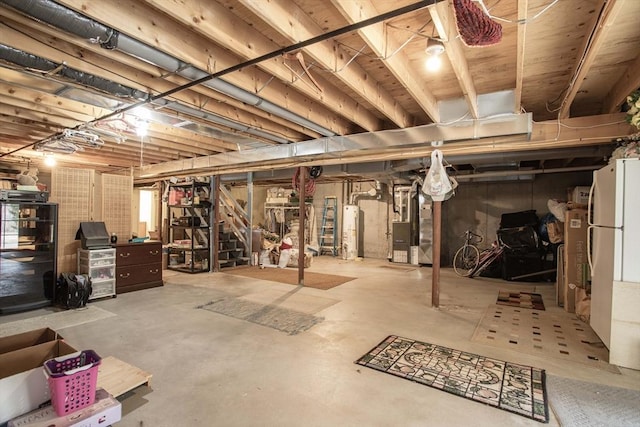 unfinished basement with freestanding refrigerator, water heater, and heating unit