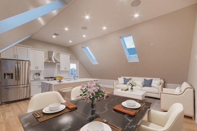 dining space with vaulted ceiling with skylight, sink, and light wood-type flooring