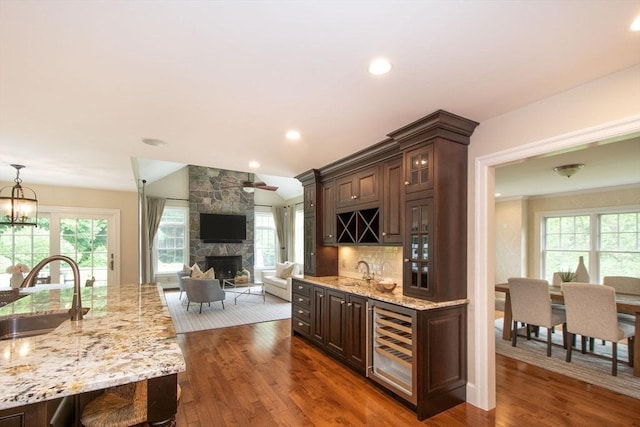 265 King St, Cohasset, MA 02025 - indoor wet bar with wine cooler, a stone fireplace, dark wood-type flooring, backsplash, and decorative light fixtures
