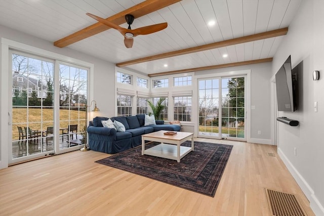 living room with a wealth of natural light, beam ceiling, and light hardwood / wood-style flooring