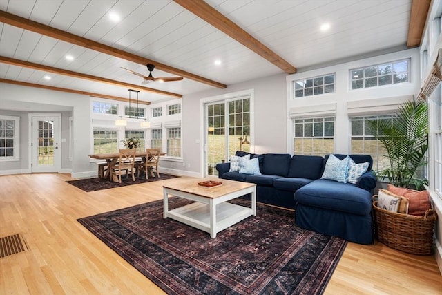 living room with plenty of natural light, beam ceiling, and light hardwood / wood-style flooring